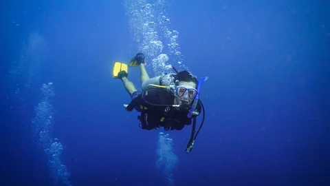 Eric scuba diving over a reef and looking toward the camera
