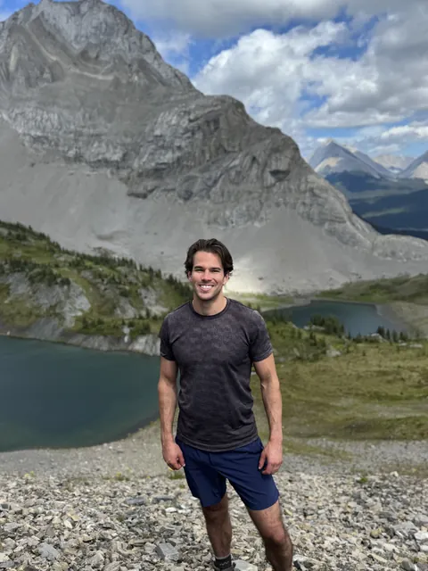Eric standing by an alpine lake with a mountain behind him